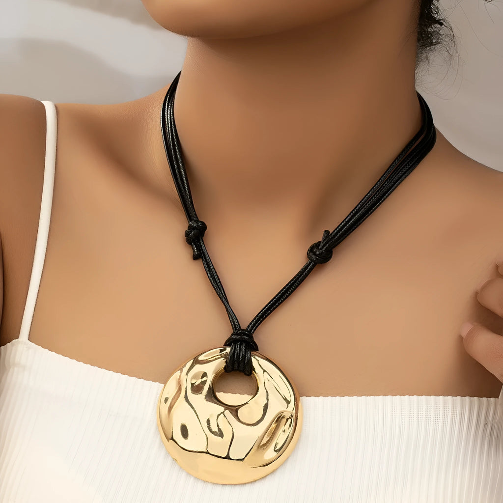 Women's gold alloy oval pendant necklace with braided rope chain on a plain background