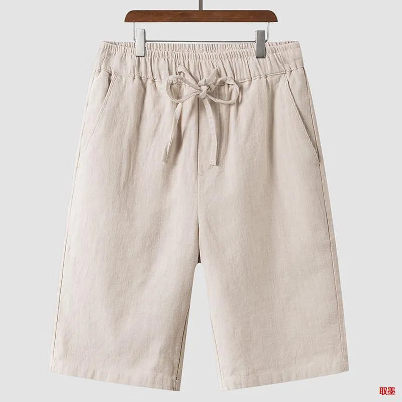 Man wearing beige linen cropped shorts with a loose fit and elasticated waistband.