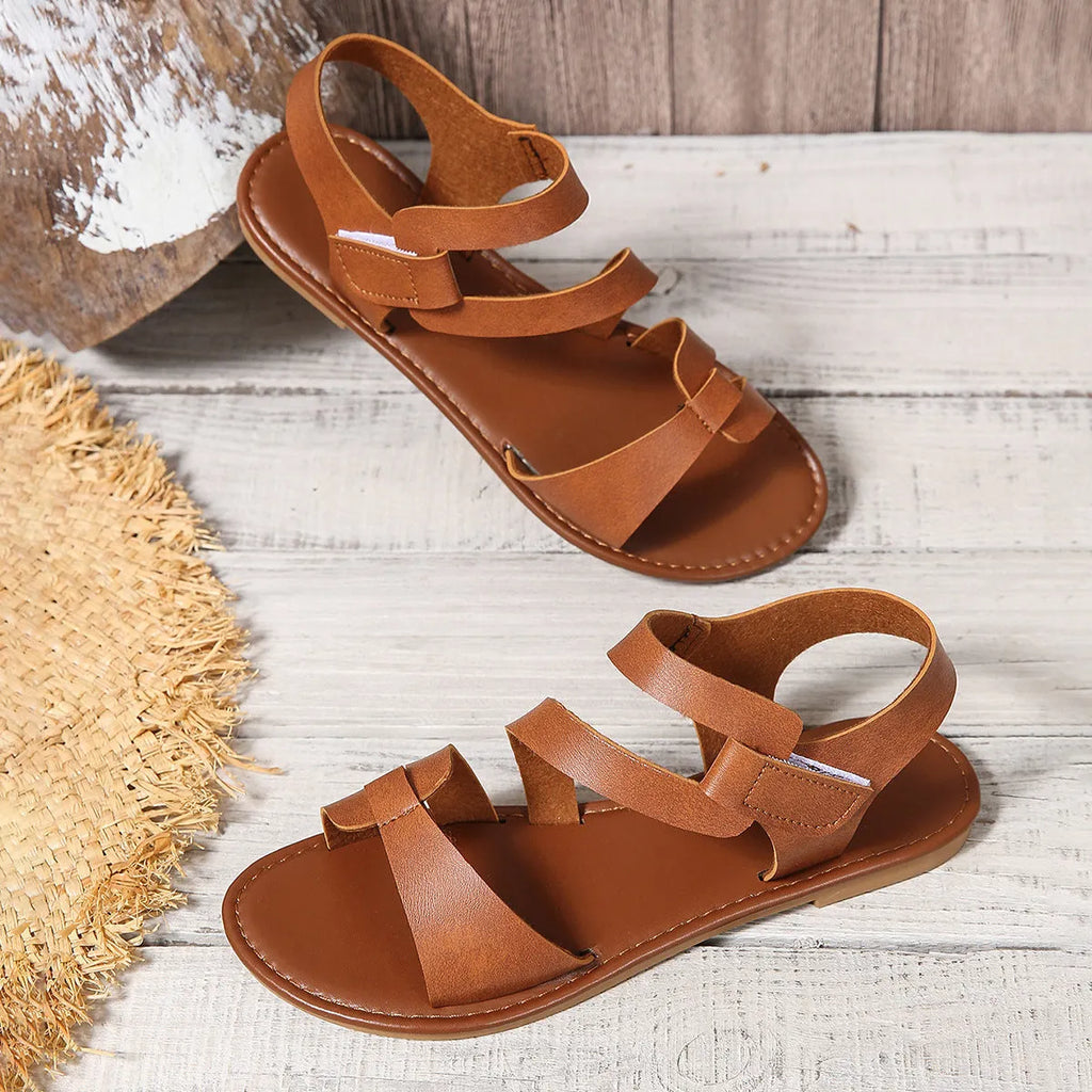 Women's black flat sandals with Velcro strap and round toe on a rubber sole.