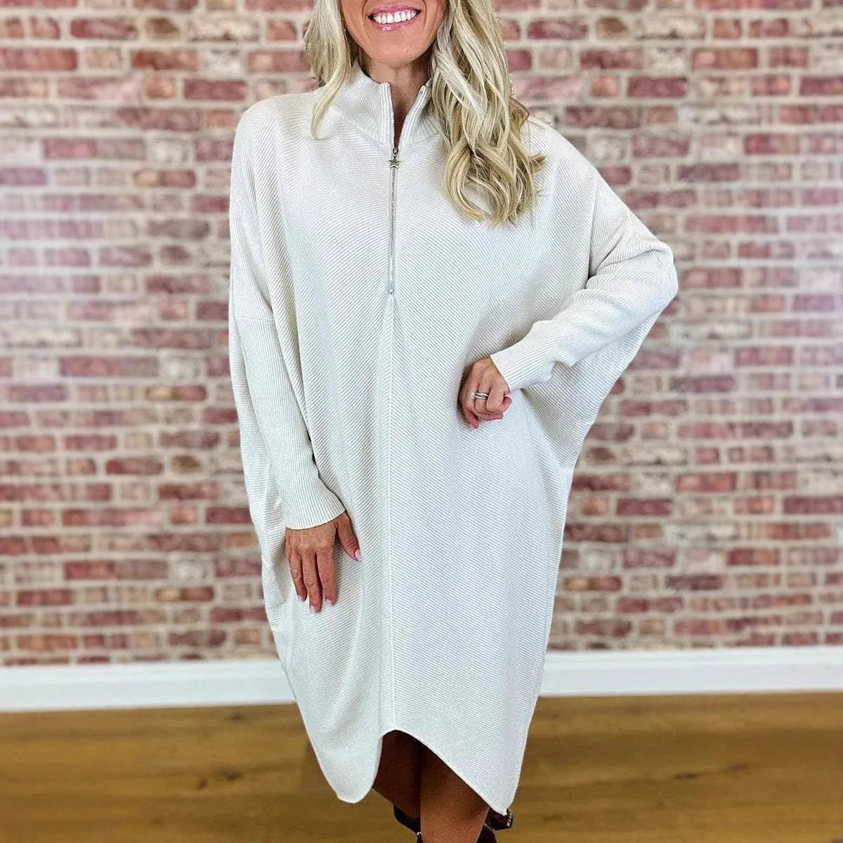 A woman wearing a loose-fitting solid colour knitted dress with raglan sleeves and a front zipper.