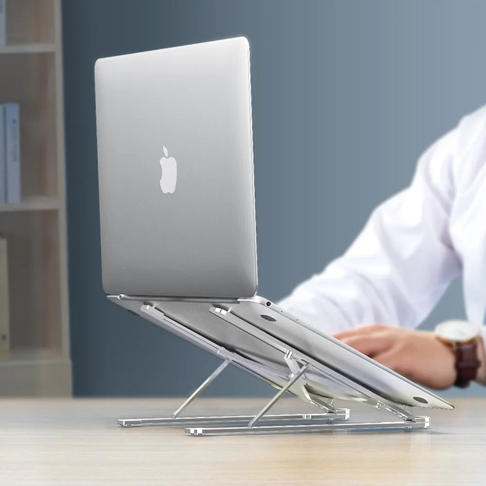 A folded deep grey aluminium laptop stand next to an open silver laptop on a desk.