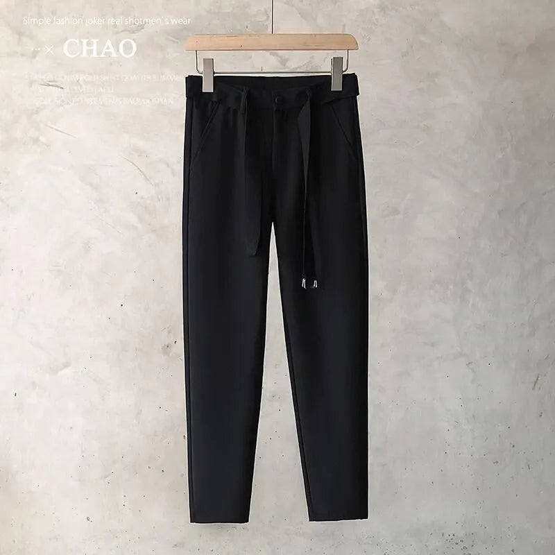 Boy wearing slim straight wool trousers in a neutral colour, showing tapered leg and straight hem.