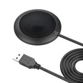 Black USB desktop microphone with metal mesh cover on a desk next to a laptop