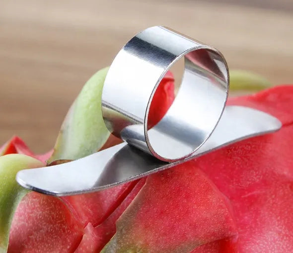 Stainless steel ring orange peeler on a countertop with citrus fruits nearby, showing compact silver tool
