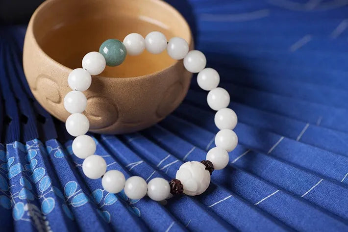 Natural white jade Bodhi bracelet with transfer beads on a neutral background