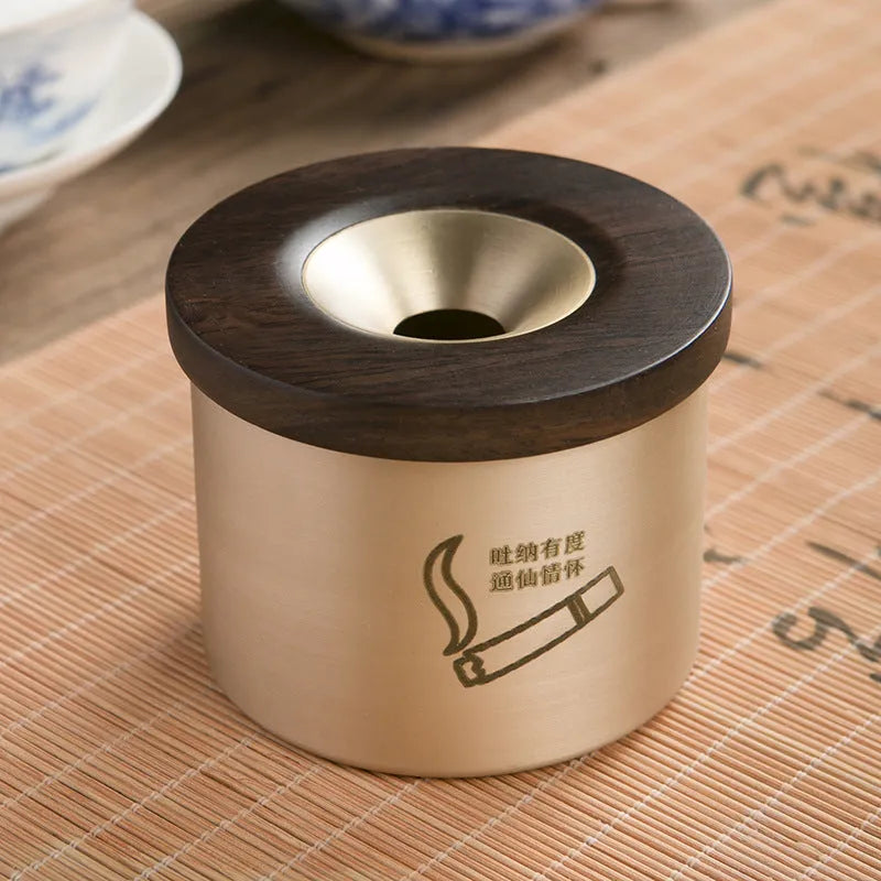 Retro-style solid copper ashtray with a wooden lid featuring a centre hole, shown in brass and black wood or brass and red wood.