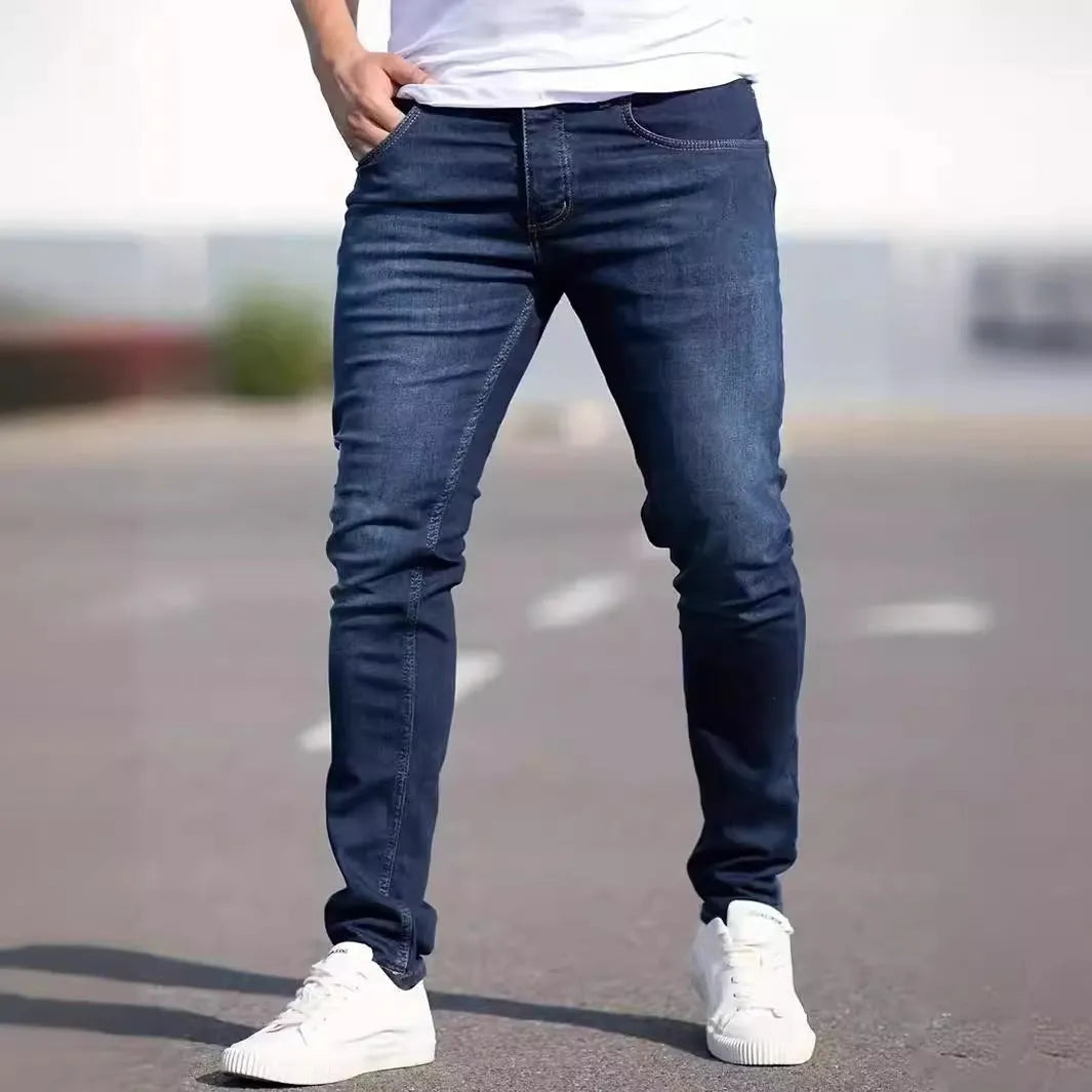 Dark blue men's skinny jeans with a mid-waist fit and zipper fly, laid flat.