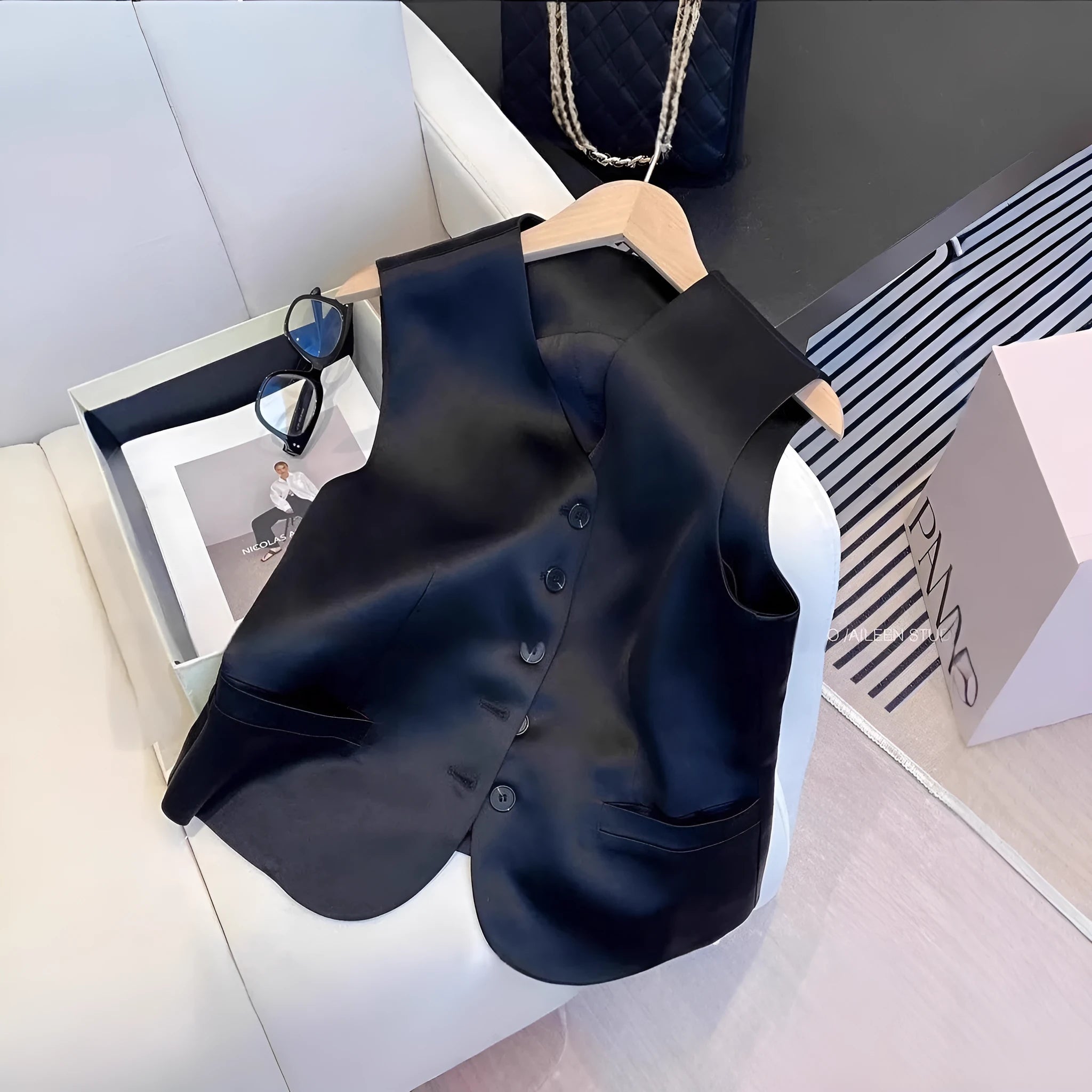 Black sleeveless satin vest for women on a hanger, showing loose fit and normal length.