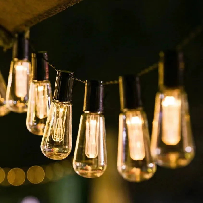 10 metre long retro infusion bottle shaped solar string lights draped outdoors with IP55 waterproof rating.
