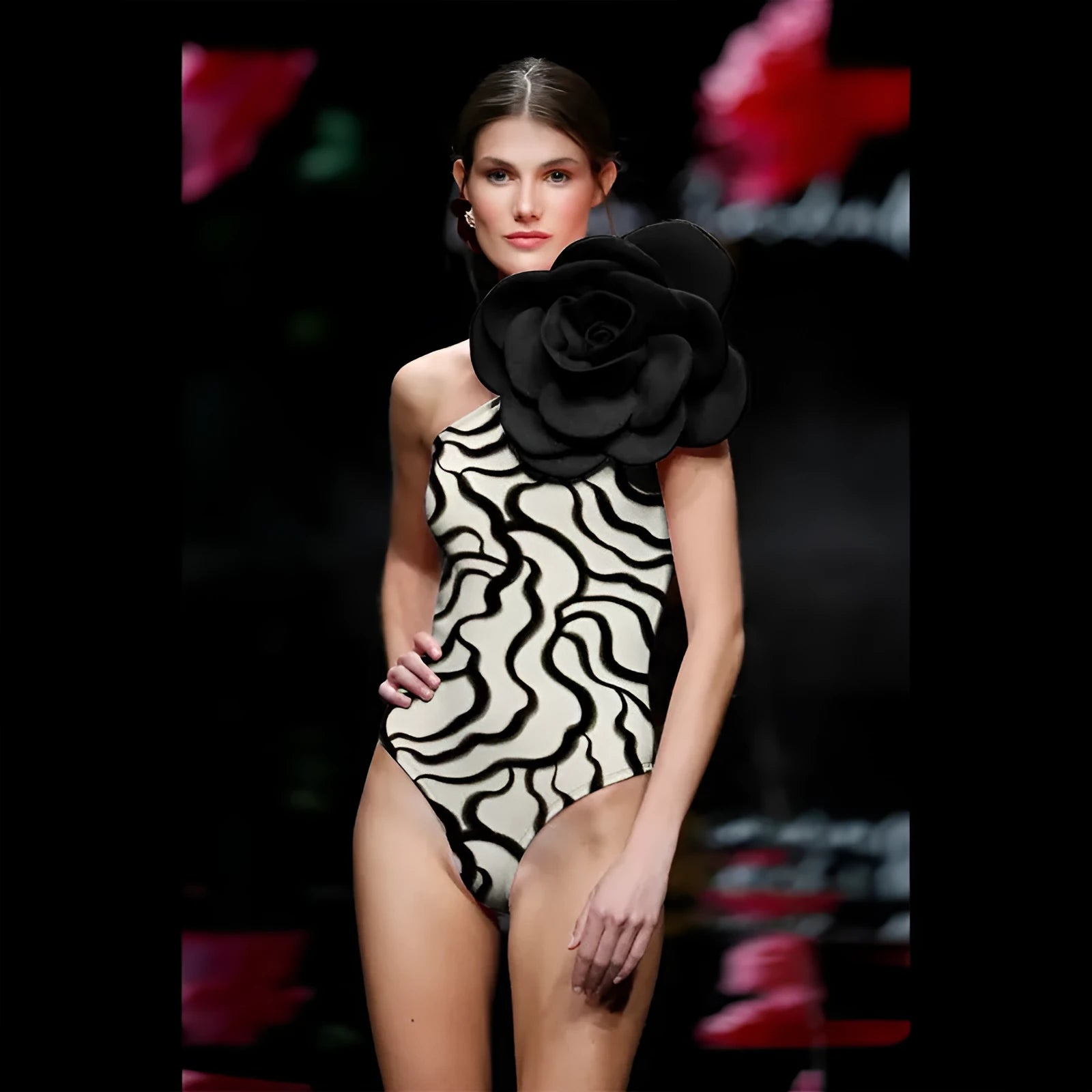 Women's one-piece swimsuit with three-dimensional floral design on black fabric.