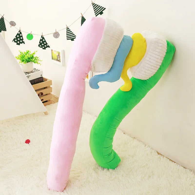 Cartoon toothbrush plush pillow 90cm in blue, green, pink, and yellow on a bed
