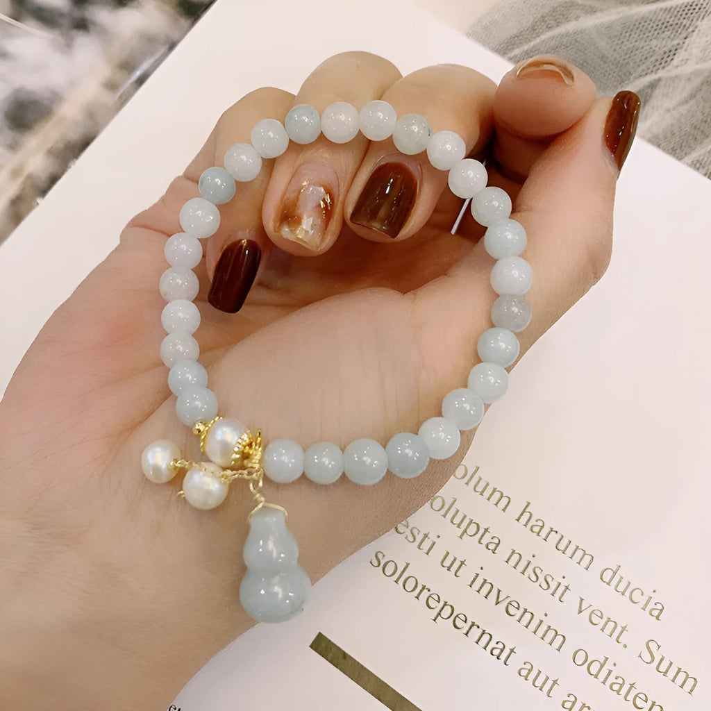 Chinese style jade bracelet with gourd charm and pearl accents on wrist