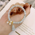 Chinese style jade bracelet with gourd charm and pearl accents on wrist