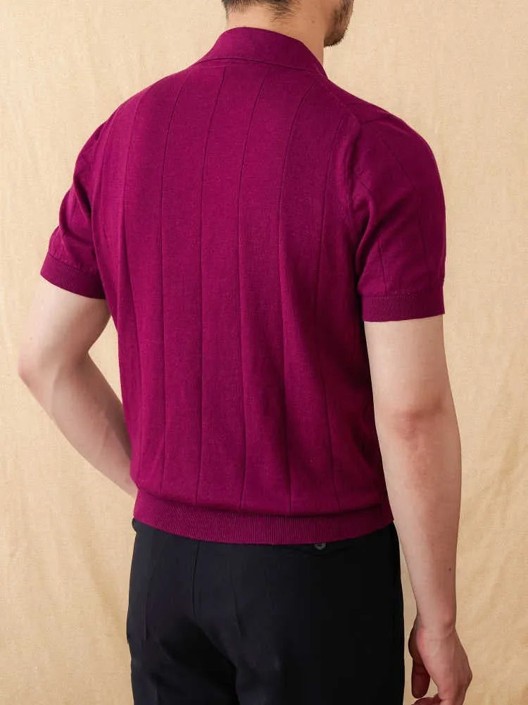 Man wearing a dark blue short sleeve polo shirt with a subtle sunken stripe knit texture and a polo collar.