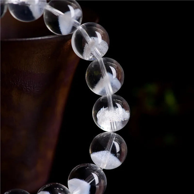 Women's white crystal bracelet with ghost pyramid beads and a ruyi charm, shown on a wrist.