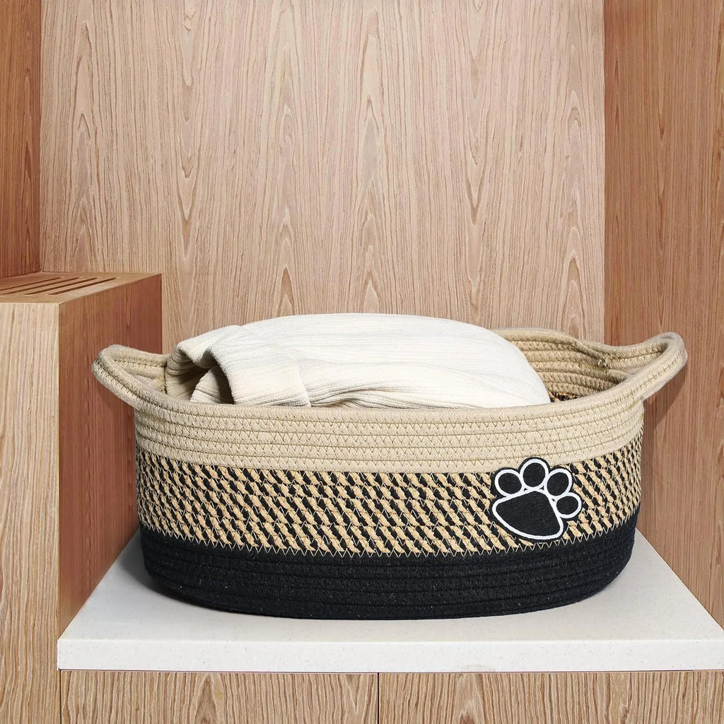 Small light beige handmade woven cotton rope storage basket with a handle on a wooden floor.