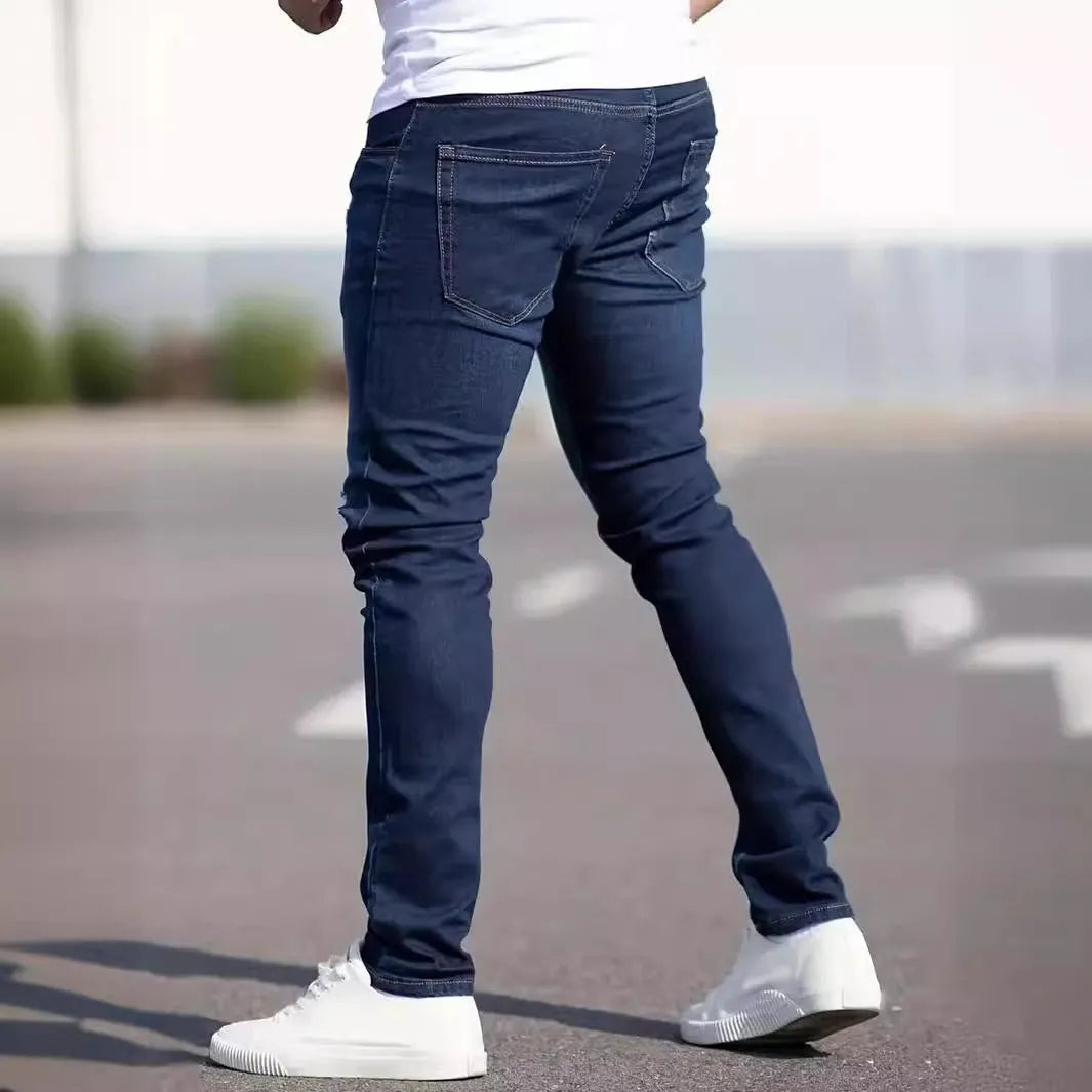 Dark blue men's skinny jeans with a mid-waist fit and zipper fly, laid flat.