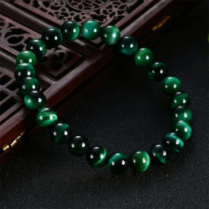 A green tiger eye stone beaded bracelet with geometric polished beads on an adjustable cord.