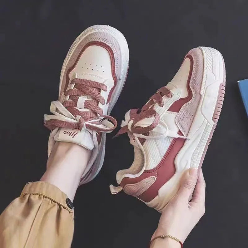 Pink and white low-top sneaker with a height-increasing rubber sole.