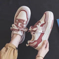 Pink and white low-top sneaker with a height-increasing rubber sole.