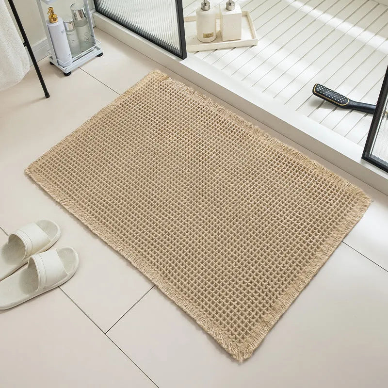 Checkered patterned non-slip absorbent bathroom floor mat in a neutral colour on tiles.