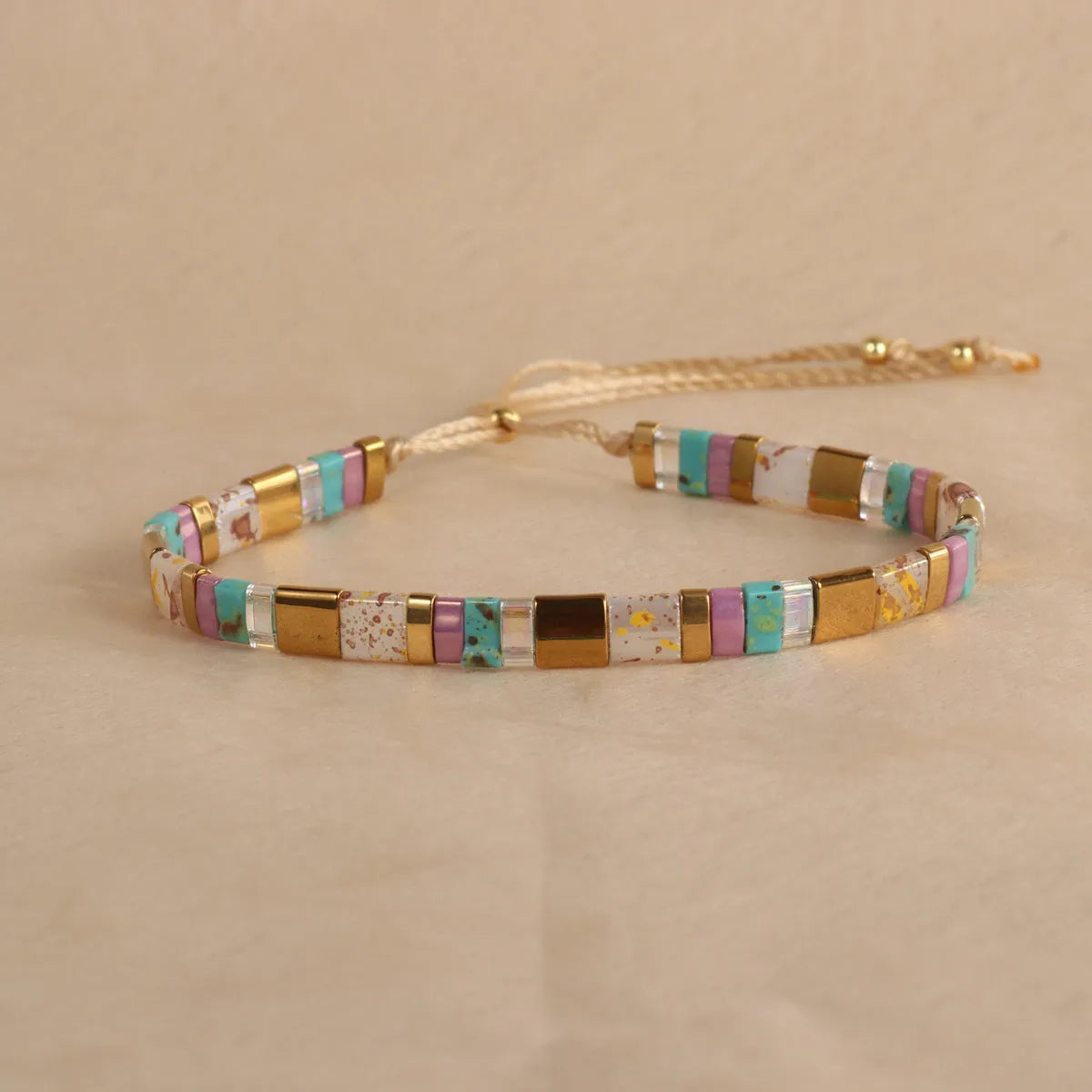 Geometric glass and coloured glaze beaded bracelet with a pull clasp in milky white colour.