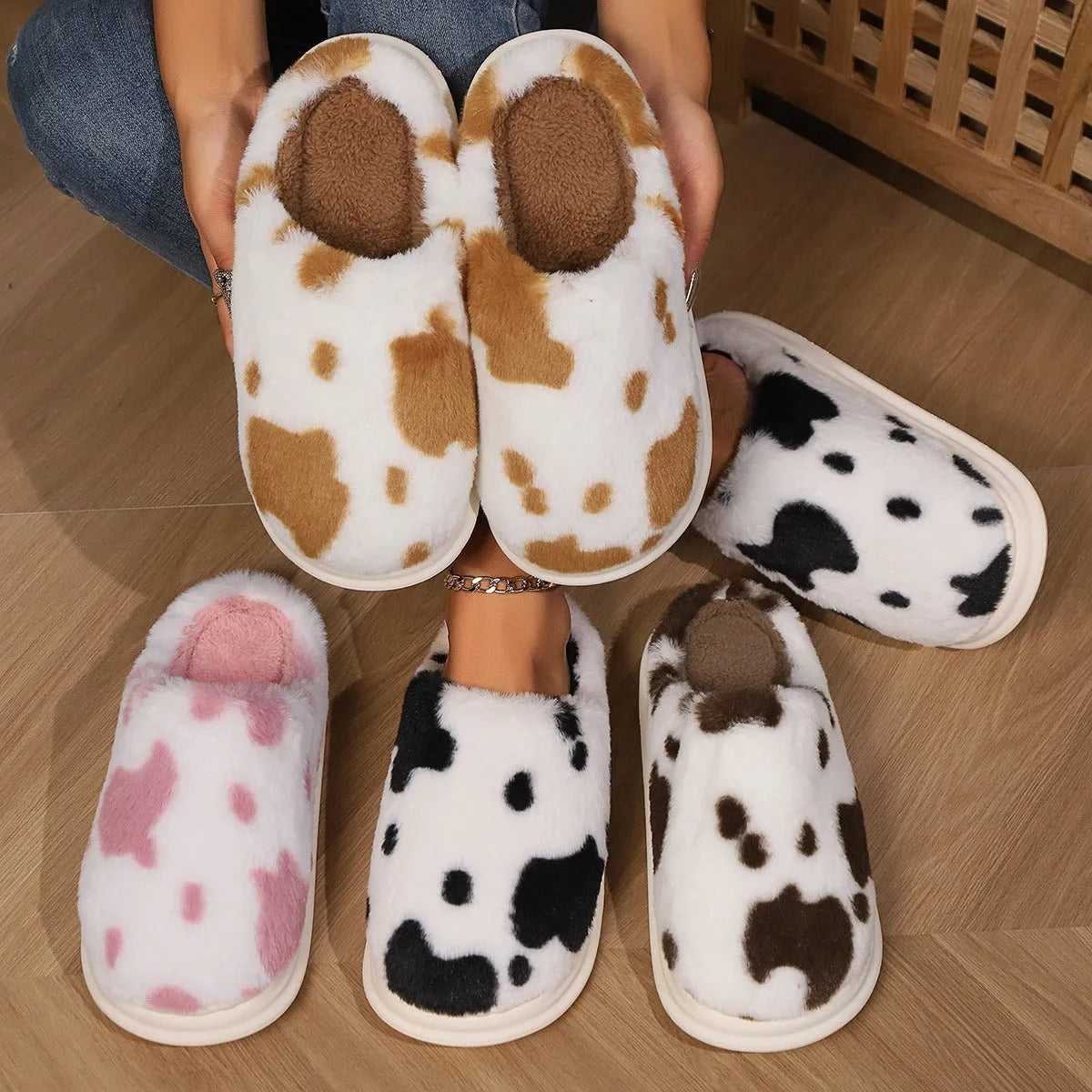 Cow spotted plush slippers in brown with round toe and baotou style on a home floor