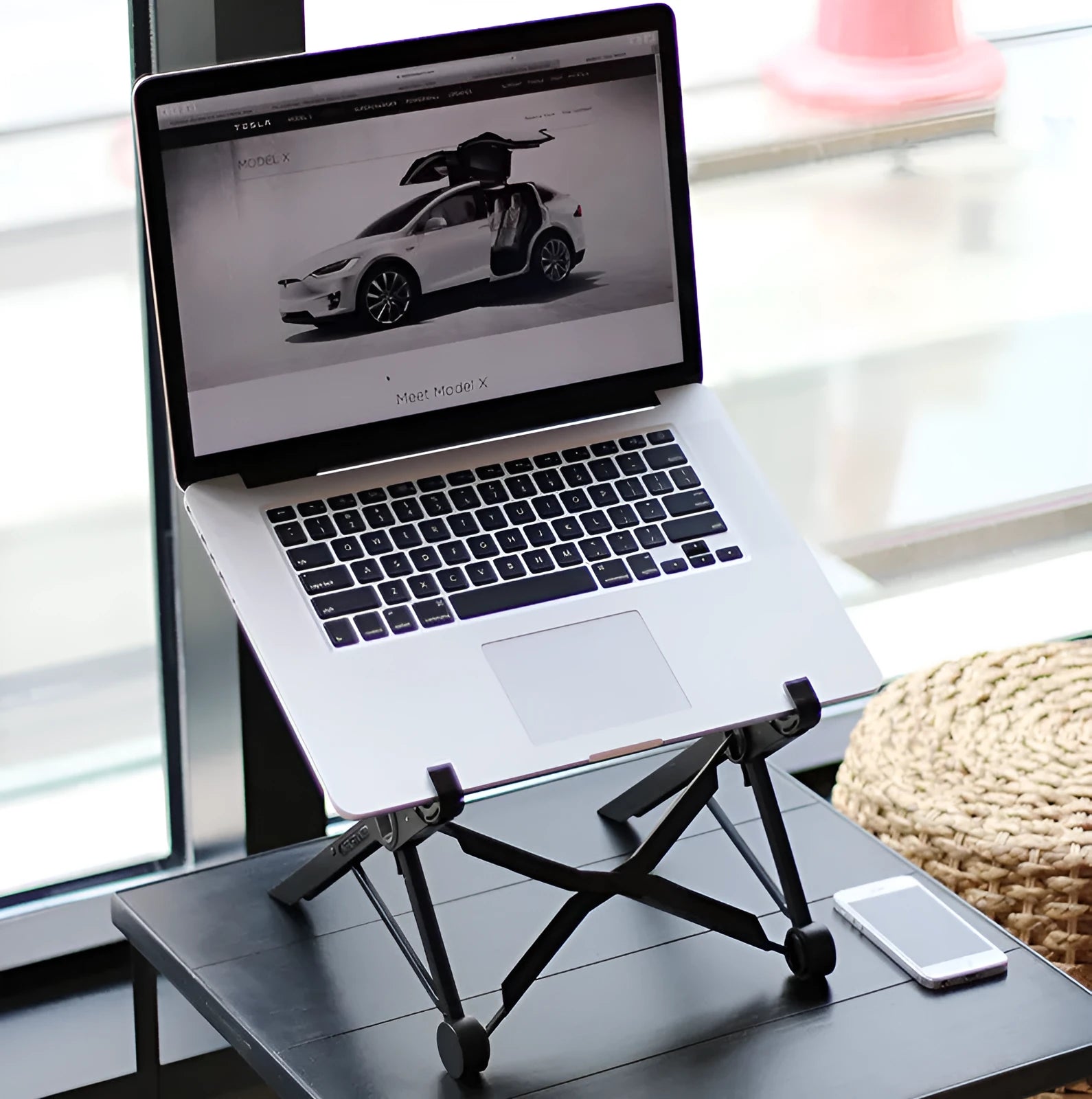 Black folding portable laptop stand made of reinforced nylon, shown in open and closed positions.