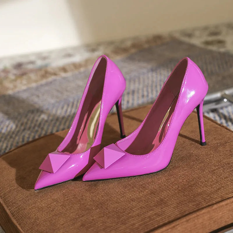 Pink pointed toe stiletto high heels with rivet detail and a buckle on the patent leather upper.