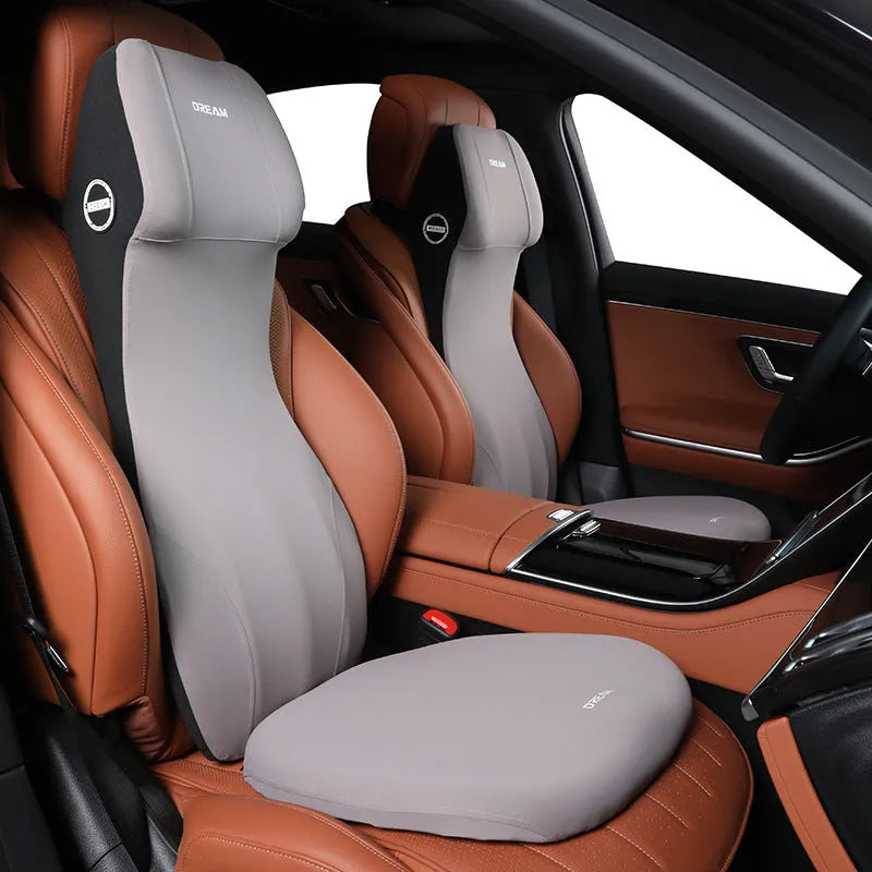 Black memory foam automotive lumbar support cushion with integrated headrest on a car seat.