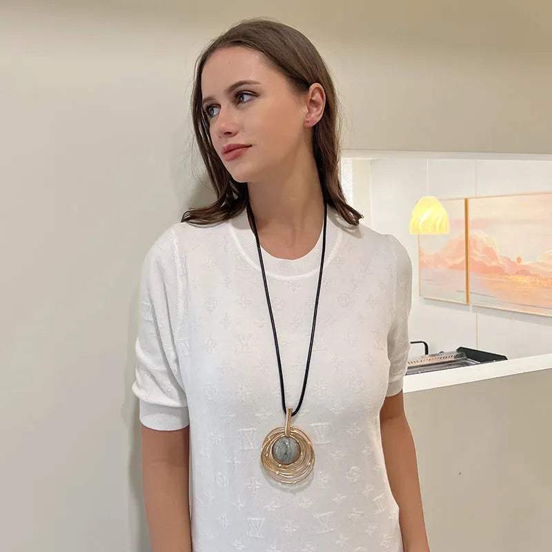 Gold geometric alloy pendant on a brown snakeskin wax rope chain necklace laid flat.