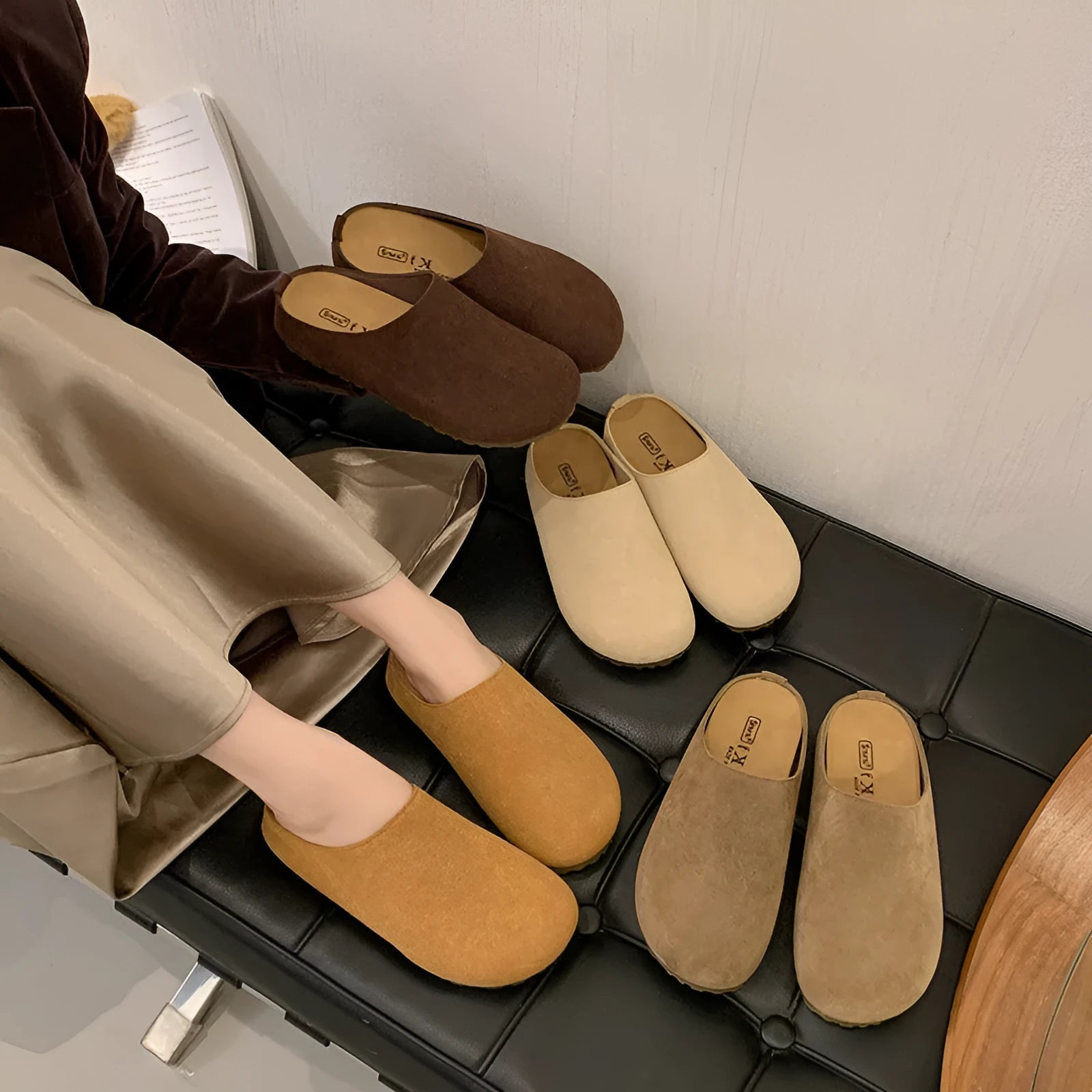 A pair of soft, flat apricot-coloured slip-on slippers with a square toe and microfiber upper on a plain background.