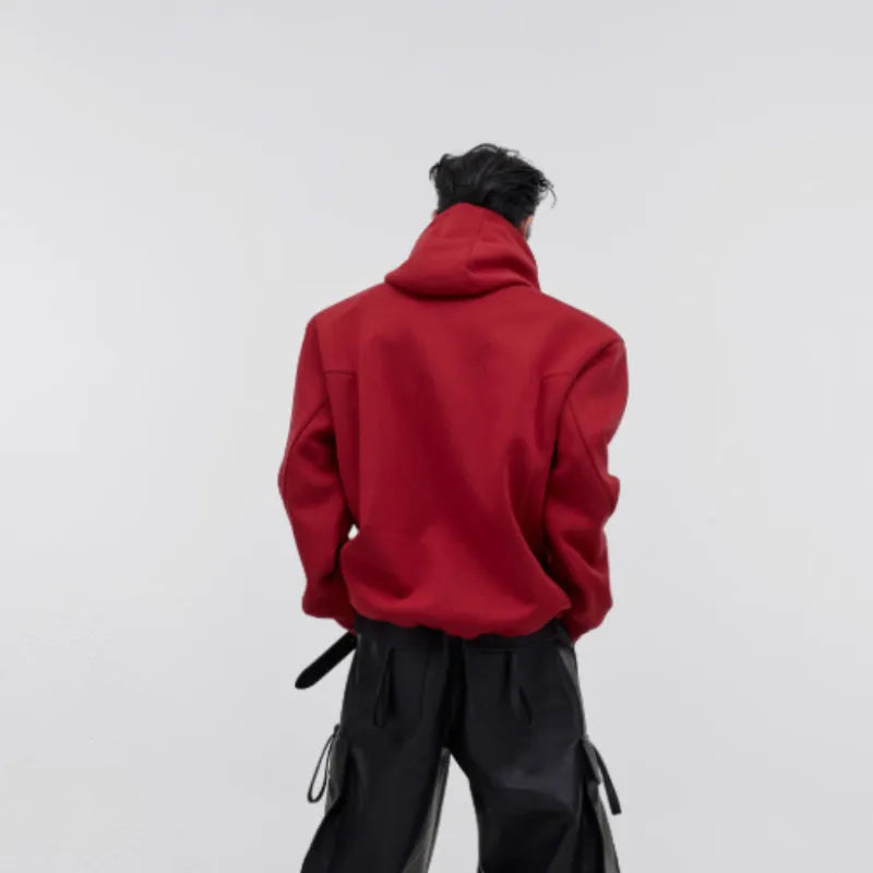 A man's loose black hooded sweater with heavy shoulder pads and a metallic three-dimensional printed design on the front.