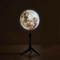 Earth and Moon projection lamp with flexible hose bracket on a table, showing USB cable.