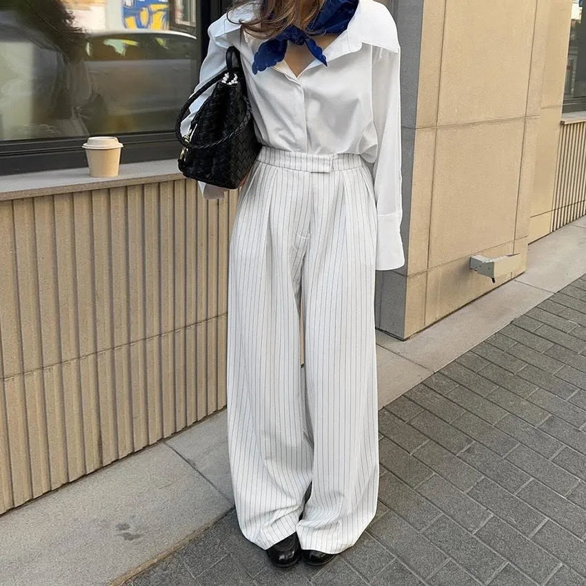 White striped wide-leg women's trousers with a loose fit and zipper fastening on a hanger.