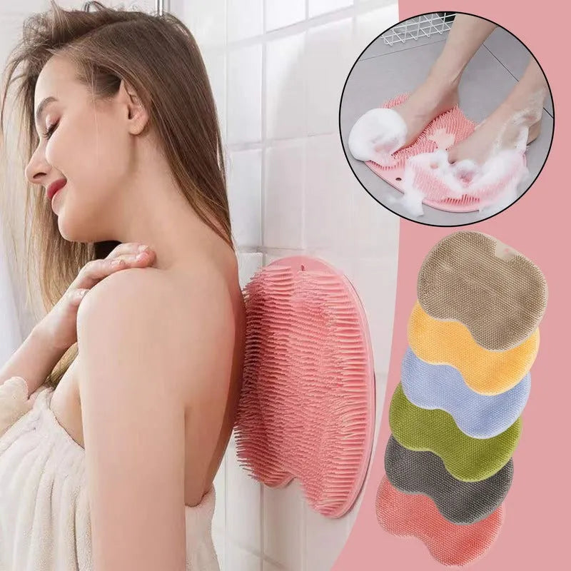 Orange silicone suction cup bath brush mat with bristles for foot and back cleaning on a bathroom floor.