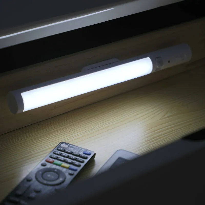 Slim white human body induction LED cabinet light with magnetic base for sticking to metal surfaces.