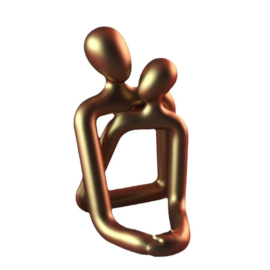 Modern minimalist resin statue of a couple in milky white or gold colour on a wooden surface.