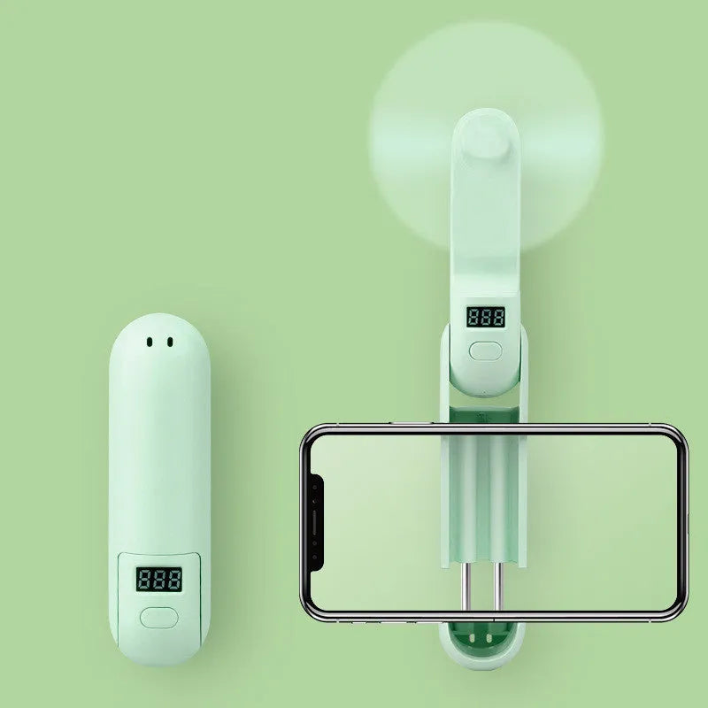 Green folding USB rechargeable mini desk fan with plastic blades on a white background.