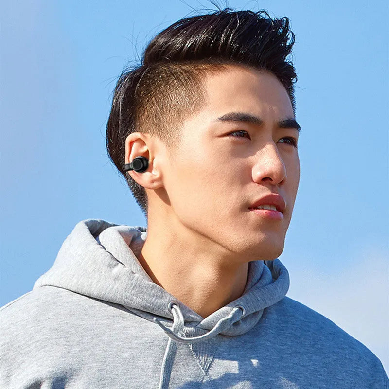 Black wireless clip-on bone conduction Bluetooth earphones shown with charging cable.