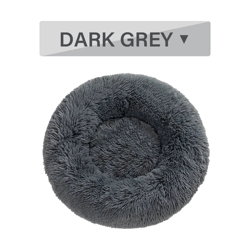 Fluffy grey donut-shaped dog bed with raised plush edge on a wooden floor.