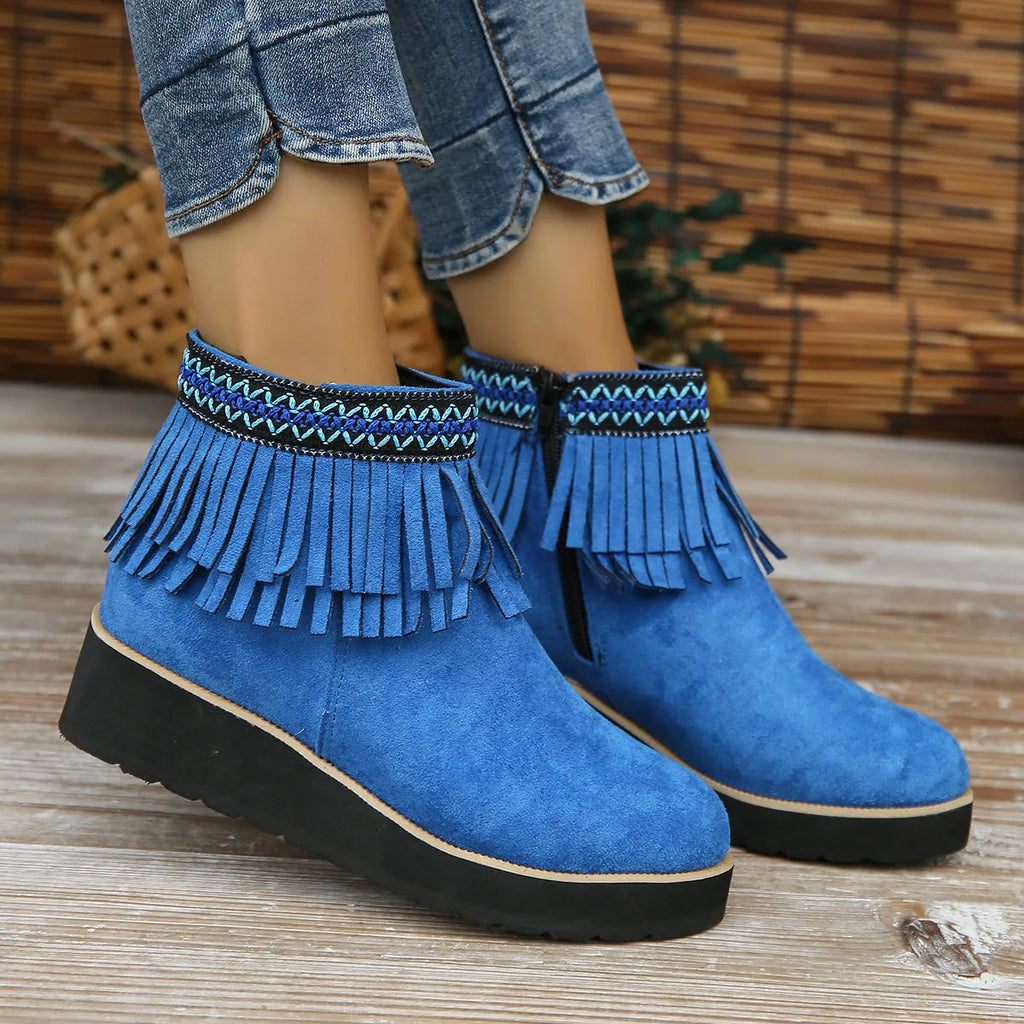 Women's suede ankle booties with a wedge heel, side zipper, tassel detail, and thick rubber sole.