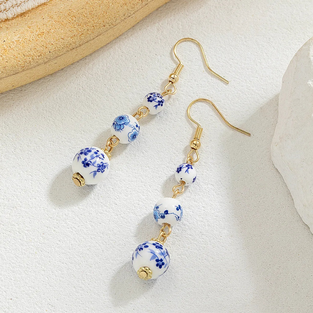 Long retro earrings with blue and white porcelain-coloured ceramic beads and geometric alloy details.