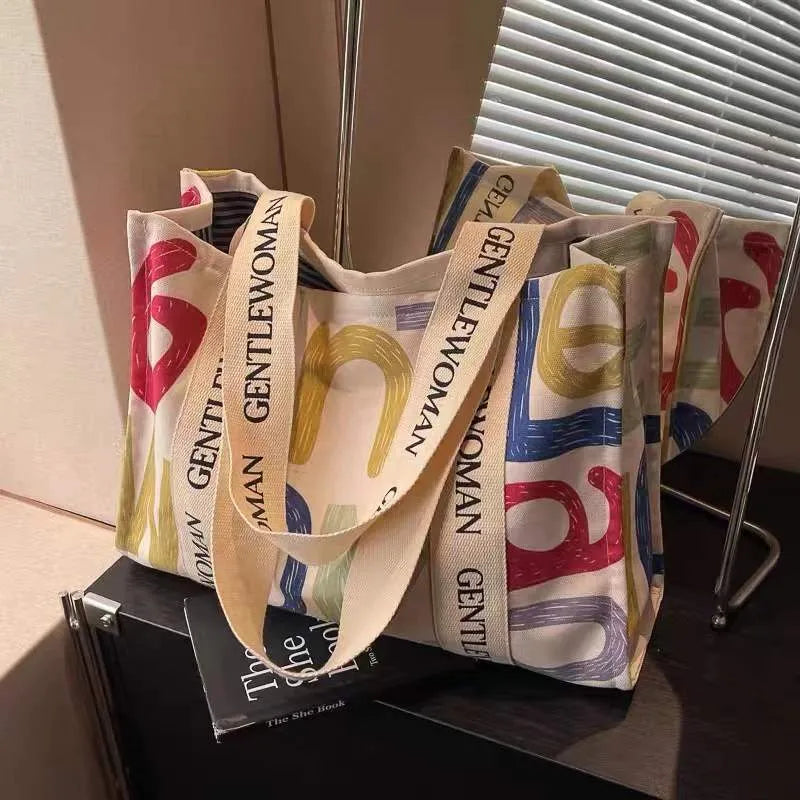 Women's large capacity canvas tote bag with printed design in three colour options.