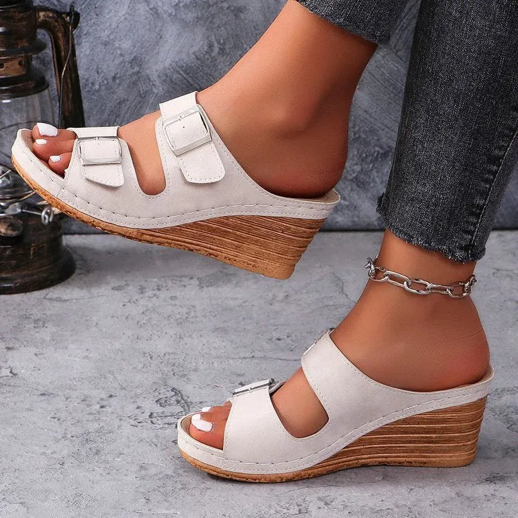 Women's creamy-white beach slippers with a black outer wedge belt buckle closure on a rubber sole.