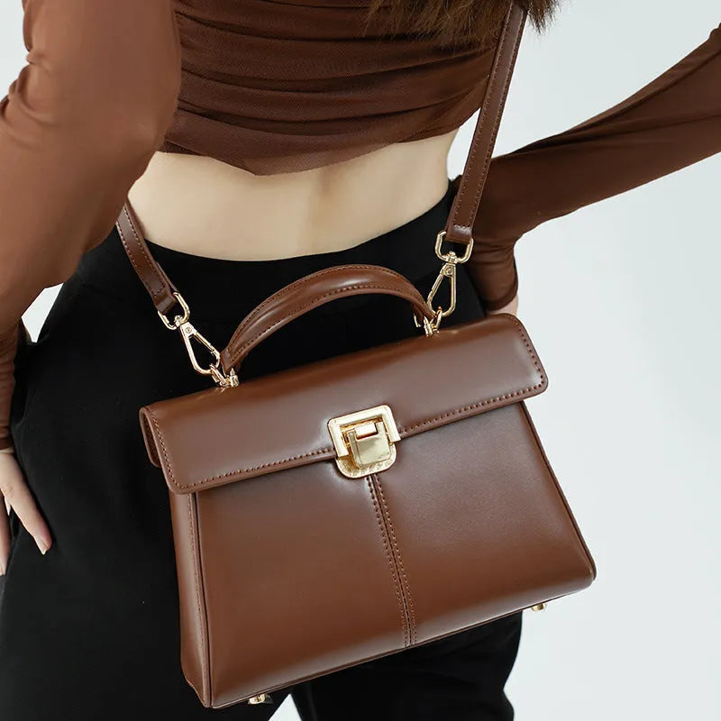 Women's black leather shoulder bag with vachette clasp showing horizontal square shape and adjustable strap