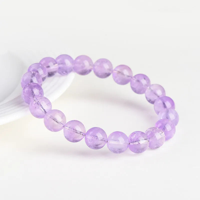 Lavender round amethyst bead bracelet with geometric water ripple design on a wrist.