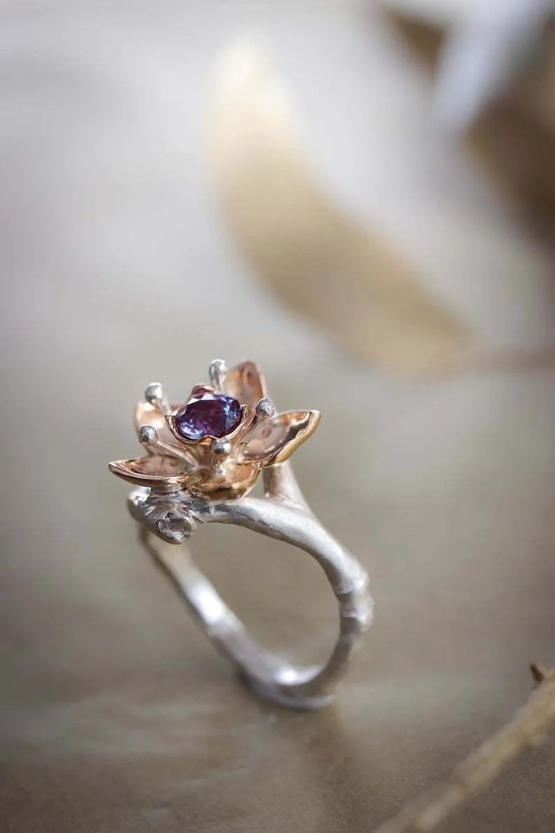 Silver two-tone women's ring with geometric shape and floral detailing on a hand.