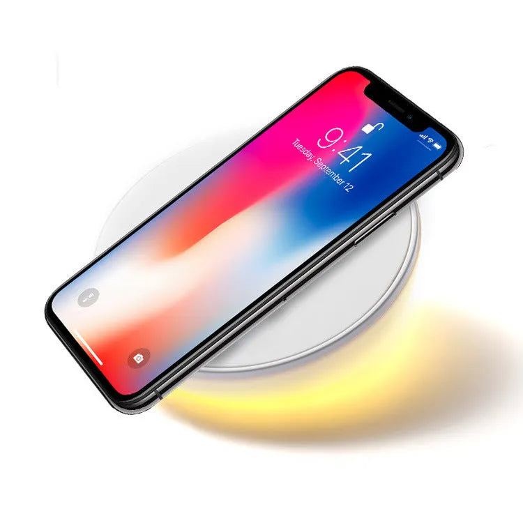 White wireless charging pad with LED digital clock display and control buttons on a desk.