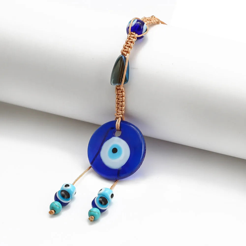 Glass evil eye bead ornament with Turkish blue eye pattern and braided string for wall or car hanging